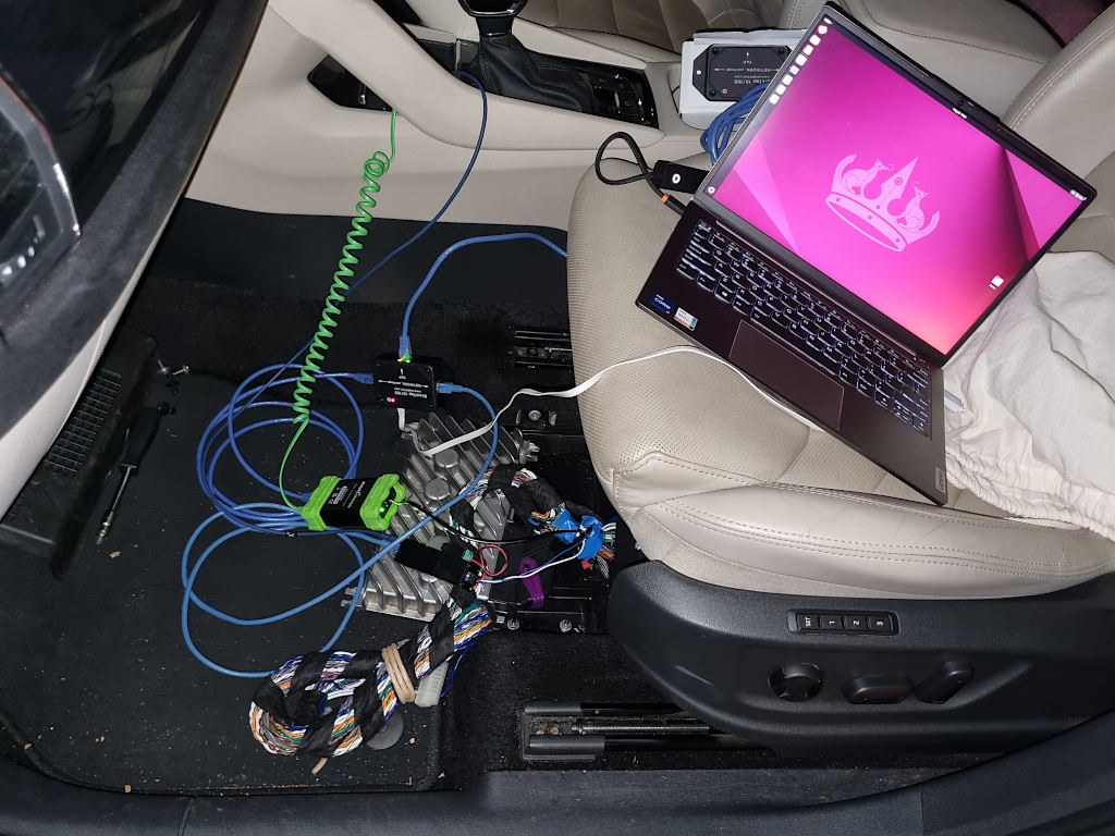 Lots of wires inside the car connected with two ethernet adapters, a network tap and a laptop